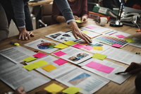 people collaborating around a table with documents and sticky notes